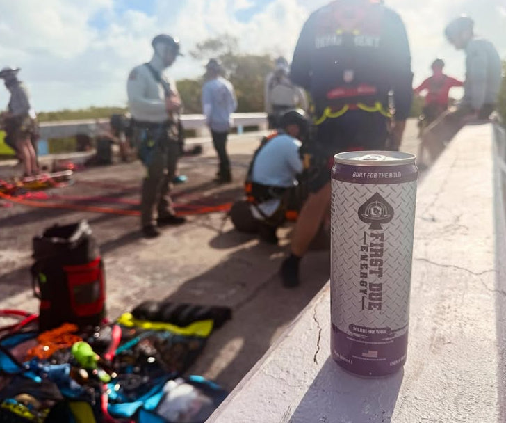 A can of First Due Energy Drink with is shown in sharp focus in the foreground, resting on a concrete ledge at a rope rescue class.